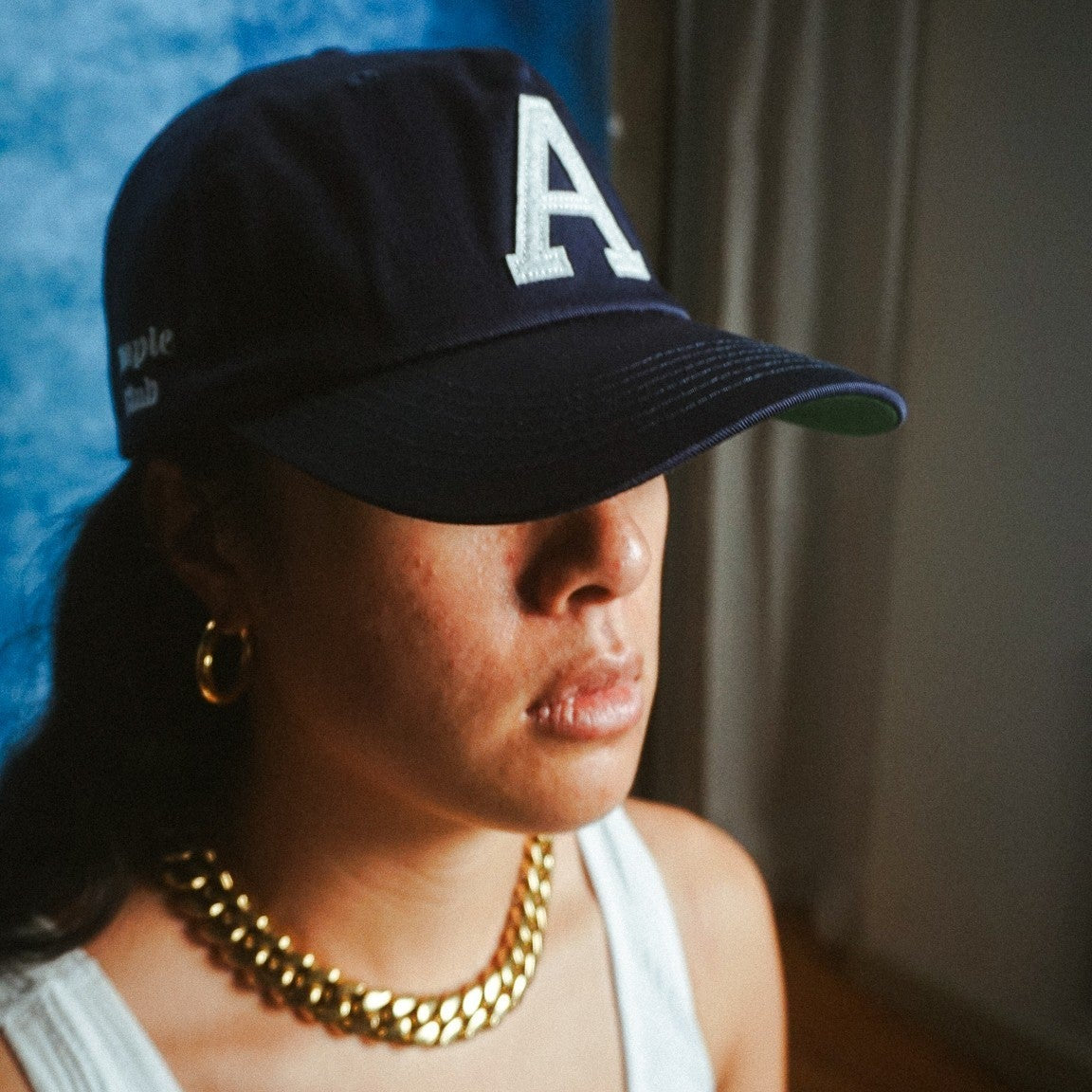 AMPLE navy blue cotton twill baseball cap with white embroidered A logo and side script worn by a woman
